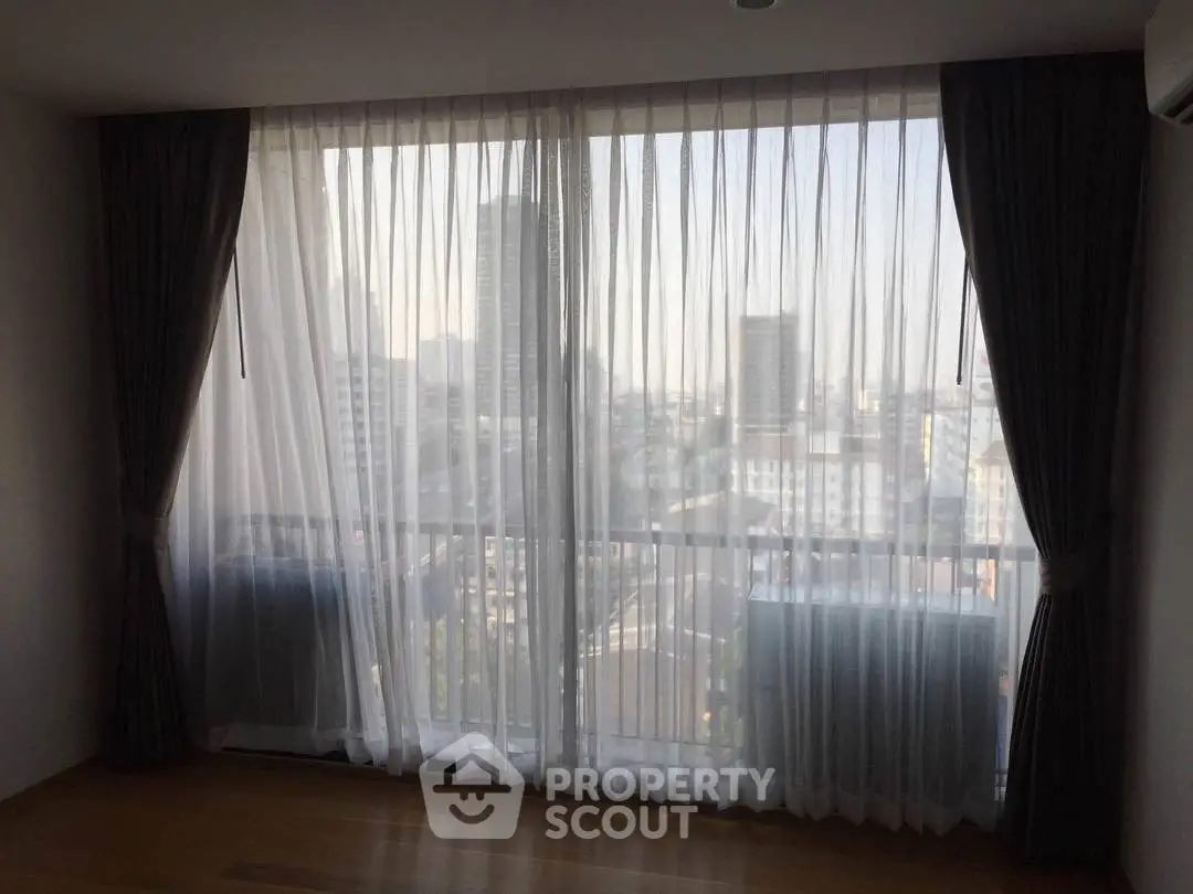 Spacious room with large windows offering a stunning city view, perfect for urban living.