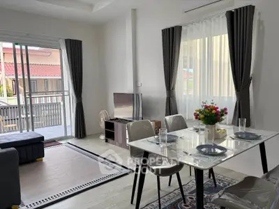 Modern living room with dining area, large windows, and stylish decor in a bright, open space.