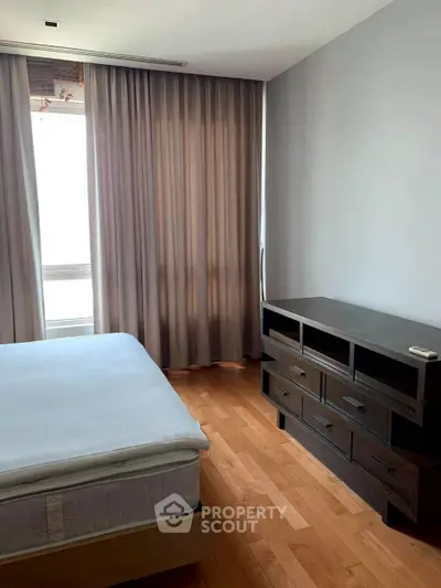 Spacious bedroom with wooden flooring and modern furniture