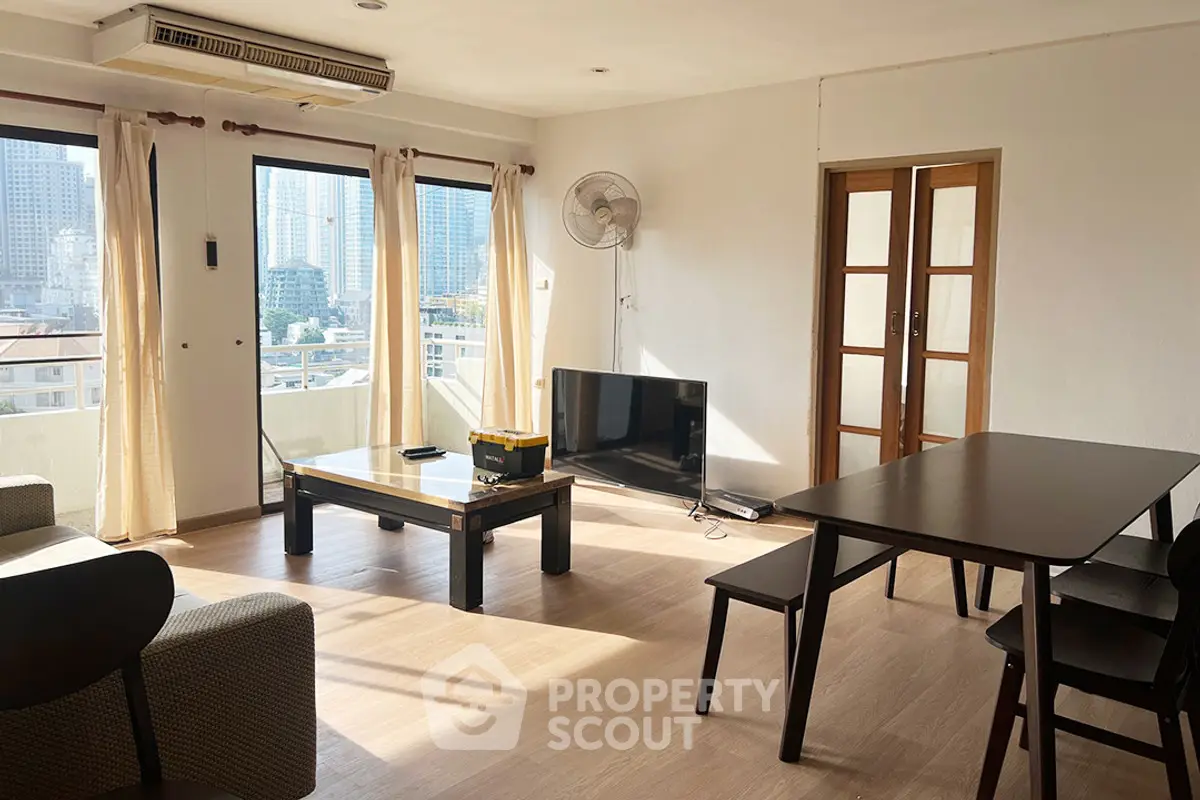 Spacious living room with city view, modern furniture, and natural light.
