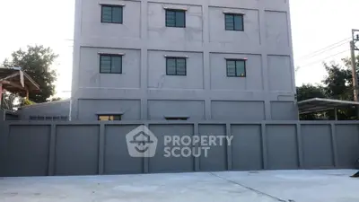 Modern gray building exterior with secure perimeter wall and spacious driveway