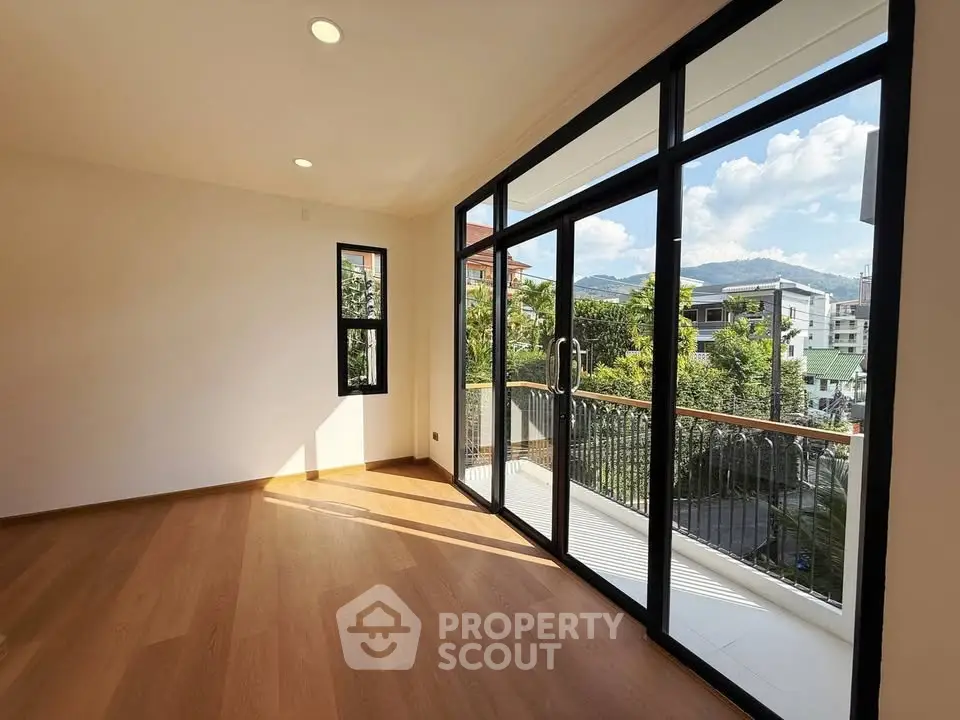 Spacious room with large windows and balcony offering stunning views of the cityscape and mountains.