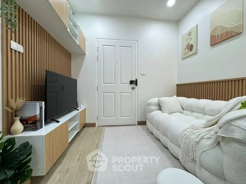 Modern living room with cozy white sofa, stylish decor, and flat-screen TV, perfect for relaxation.