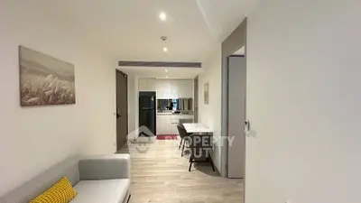 Modern open-plan living room with kitchen, featuring sleek furniture and bright lighting.