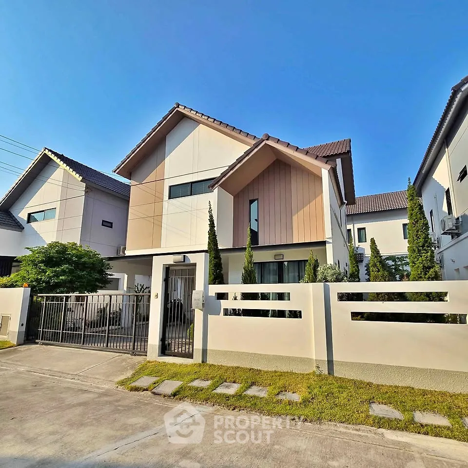 Modern two-story house with sleek design and manicured lawn in a suburban neighborhood.