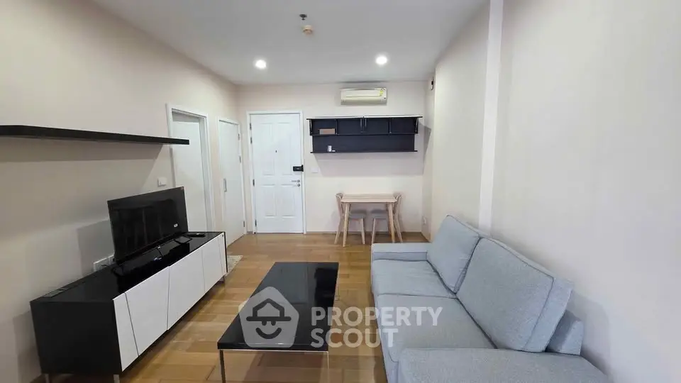 Modern living room with sleek furniture and neutral tones, featuring a cozy sofa and stylish entertainment unit.