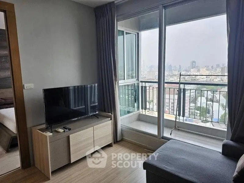 Modern living room with city view and balcony access in high-rise apartment.
