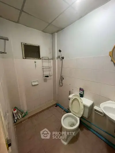 Simple bathroom with shower, toilet, and sink in a modest real estate property.