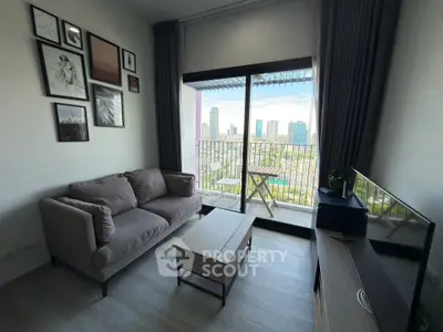 Modern living room with city view, featuring a cozy sofa, wall art, and a balcony with a small table.