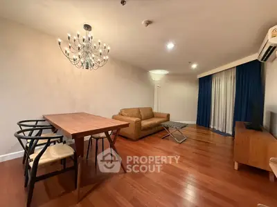 Spacious living room with elegant chandelier and hardwood floors in modern apartment.