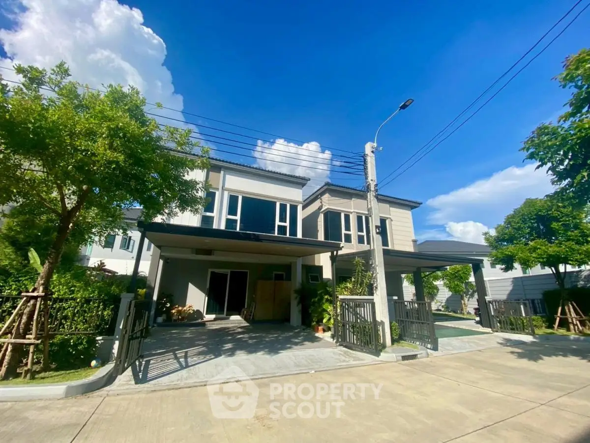 Modern two-story house with spacious driveway and lush greenery under a clear blue sky.