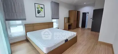 Spacious bedroom with modern decor and natural light, featuring a comfortable bed and stylish wooden flooring.