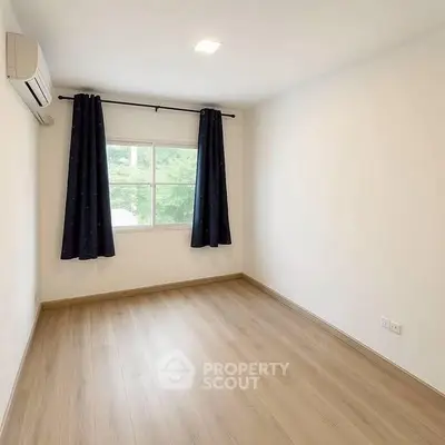 Bright empty room with wooden flooring and large window, perfect for customization.