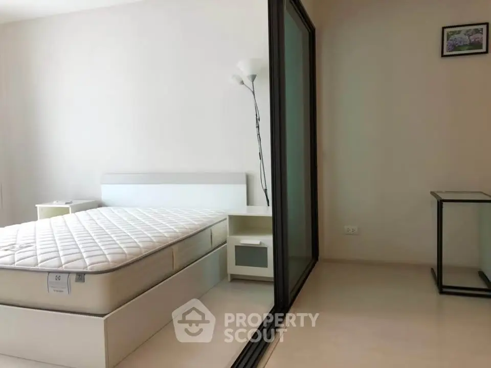 Modern minimalist bedroom with glass partition and sleek furniture design.
