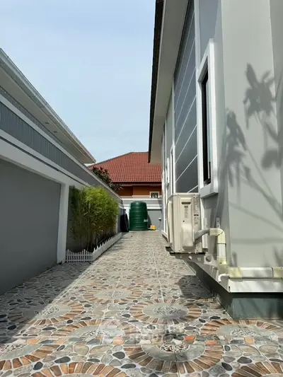 Modern exterior view of a residential property with tiled pathway and air conditioning units.