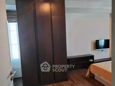 Modern bedroom with sleek wooden wardrobe and wall-mounted TV