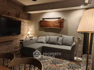 Cozy living room with stylish gray sofa and patterned tile flooring, perfect for relaxation and entertainment.