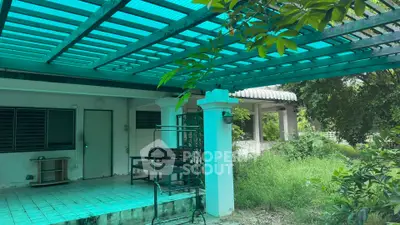 Charming outdoor patio with lush greenery and covered seating area, perfect for relaxation.
