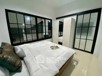 Modern bedroom with large windows and sleek design, featuring a cozy bed and stylish wardrobe.
