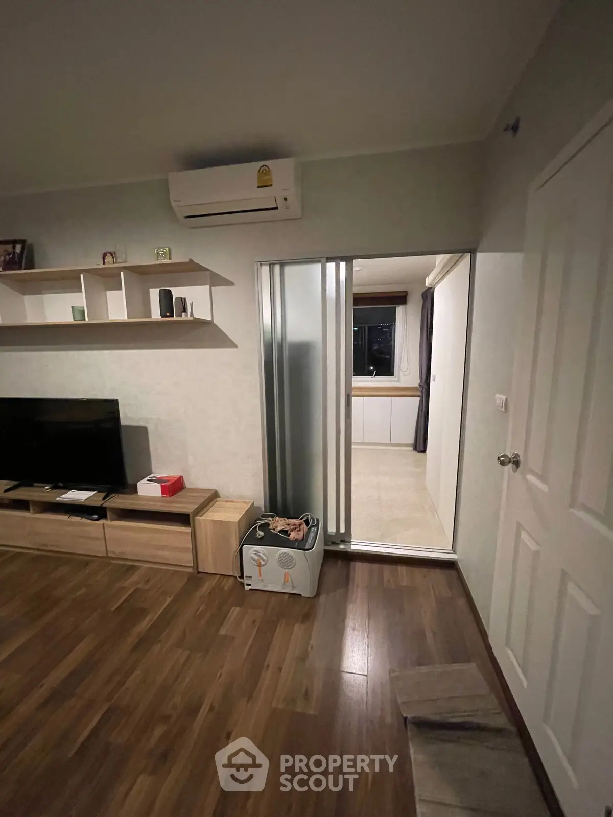 Modern living room with wooden flooring, air conditioning, and sliding door to adjacent room.