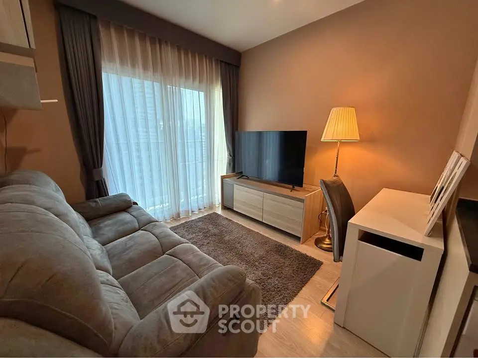 Cozy living room with plush sofa, large TV, and elegant floor lamp, perfect for relaxation.
