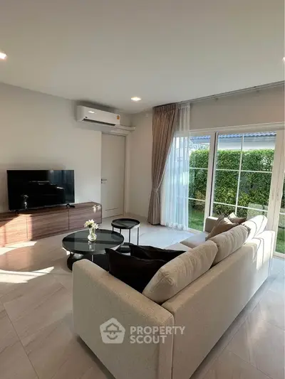 Modern living room with cozy sofa and large window overlooking garden