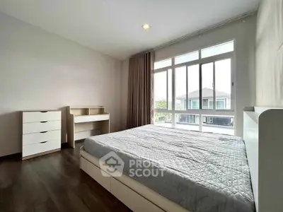 Spacious bedroom with large window and modern furniture in a bright, airy setting.