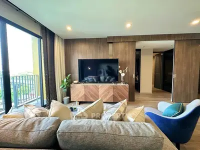 Modern living room with large TV, stylish furniture, and balcony view.