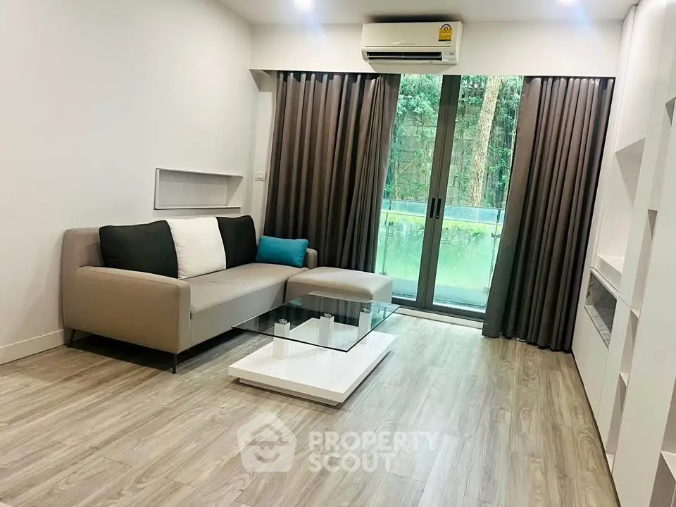 Modern living room with sleek sofa, glass coffee table, and balcony view in stylish apartment.