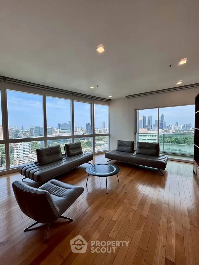 Spacious living room with panoramic city views and modern furniture in a high-rise apartment.