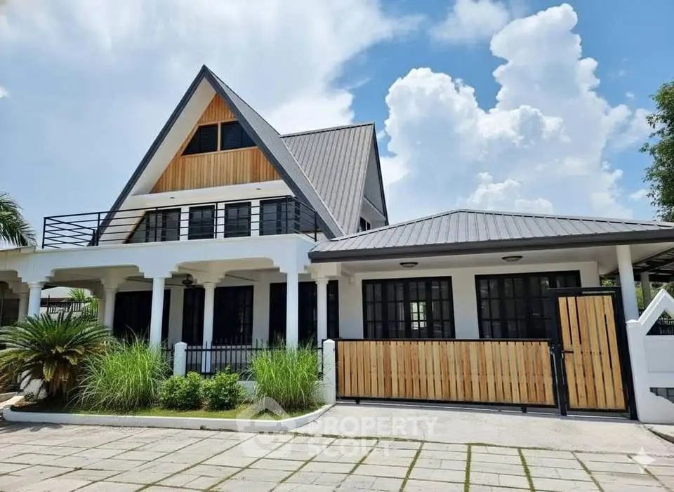 Charming modern house with unique A-frame design and lush landscaping under a bright blue sky.