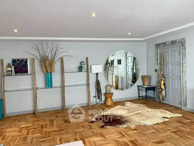 Stylish living room with parquet flooring, unique decor, and large round mirror