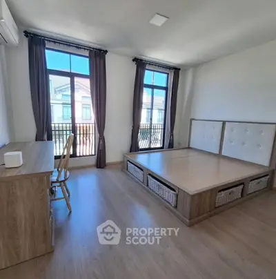 Spacious bedroom with large windows and modern wooden furniture