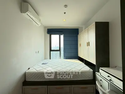 Modern bedroom with large window and built-in storage in high-rise apartment.