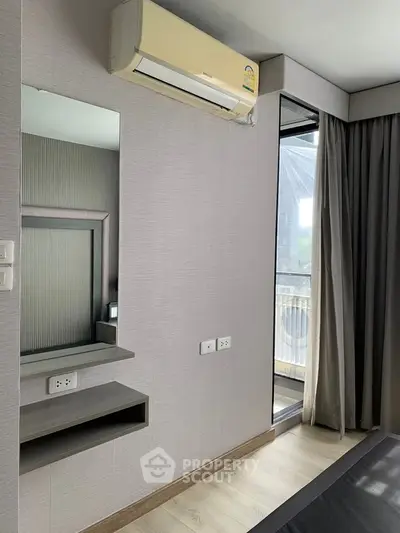 Modern bedroom with air conditioning and balcony view, featuring sleek design and natural light.