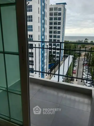 Modern apartment balcony with ocean view and nearby high-rise buildings.