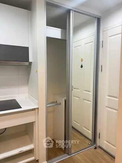 Modern apartment interior with sleek kitchen and mirrored closet doors.