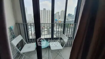 Charming balcony with city view, featuring cozy seating and modern high-rise backdrop.