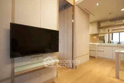 Modern open-layout living room with wall-mounted TV and sleek kitchen design.