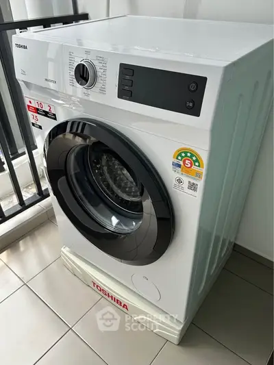 Modern Toshiba washing machine on tiled balcony with railing view.