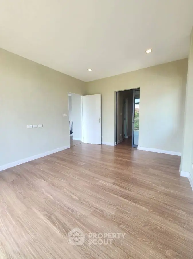 Spacious empty room with wooden flooring and bright natural light
