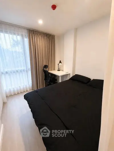 Cozy bedroom with modern decor and ample natural light, featuring a comfortable bed and a study desk.