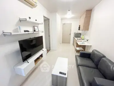 Modern living room with sleek furniture and open kitchen layout in a cozy apartment.