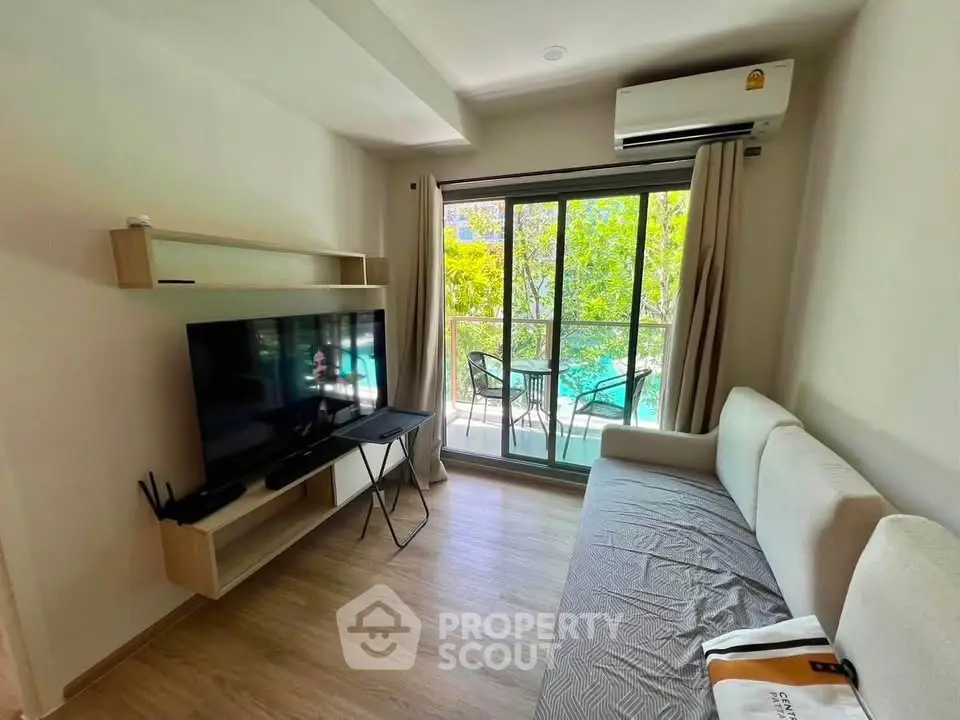 Modern living room with balcony view, featuring sleek furniture and abundant natural light.