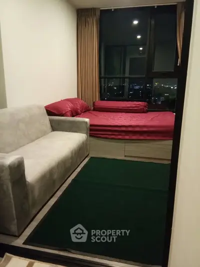 Cozy bedroom with city view, featuring a comfortable bed and modern sofa.