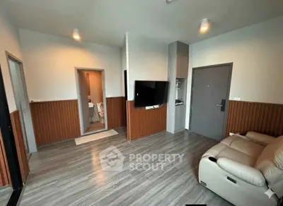 Modern living room with sleek flooring and wall paneling, featuring a cozy sofa and mounted TV.