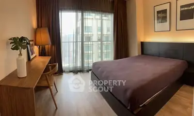 Modern bedroom with large window and stylish decor in urban apartment.