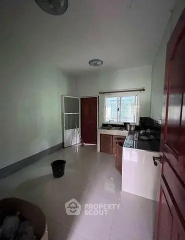 Spacious kitchen with modern design and ample natural light, featuring sleek countertops and a large window.