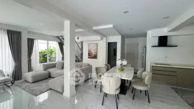 Spacious modern living room with open kitchen and elegant dining area, featuring stylish furniture and natural light.