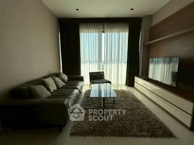 Modern living room with cozy sofa, stylish rug, and large window for natural light.
